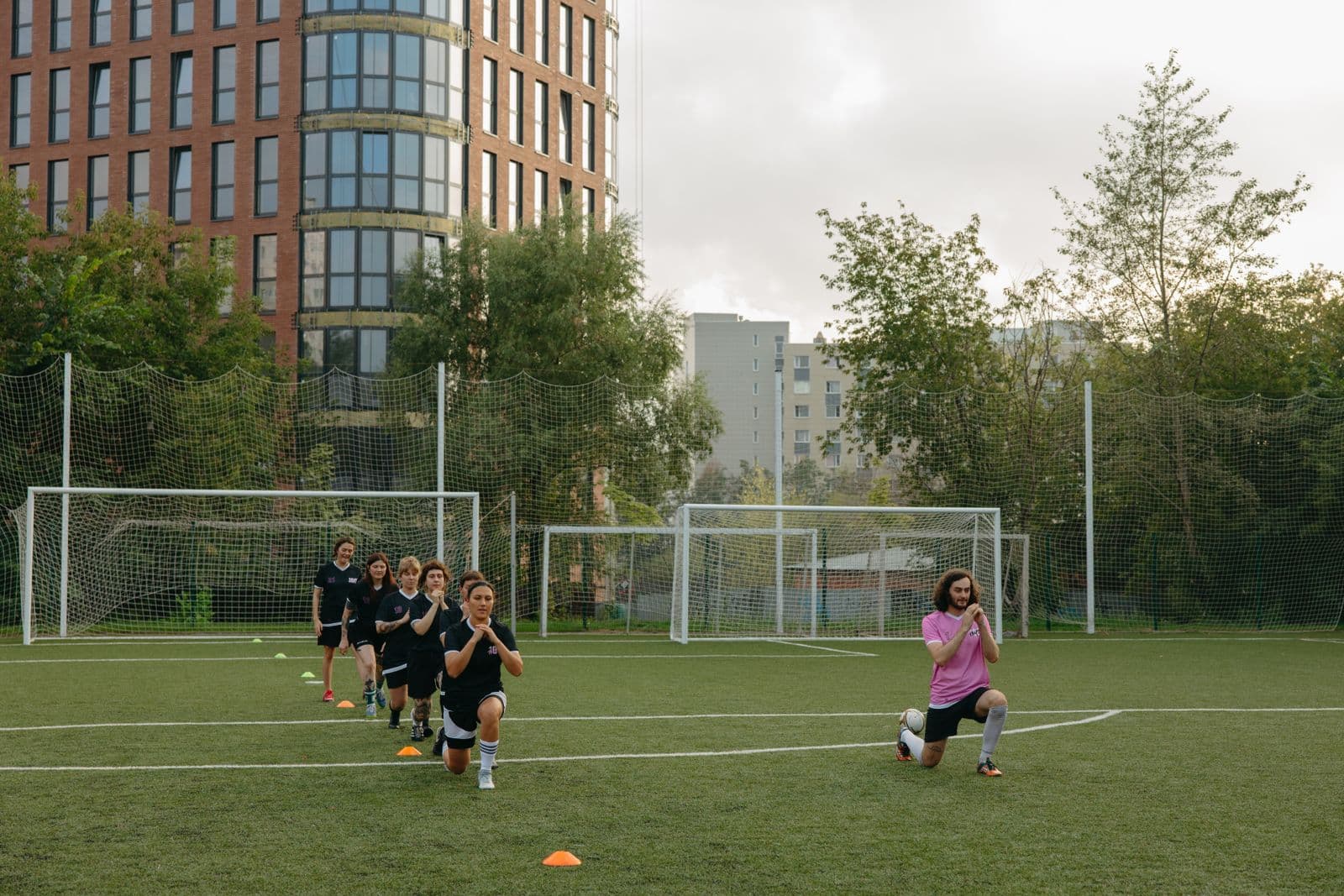 Soccer players warming up with a coach on a training field
