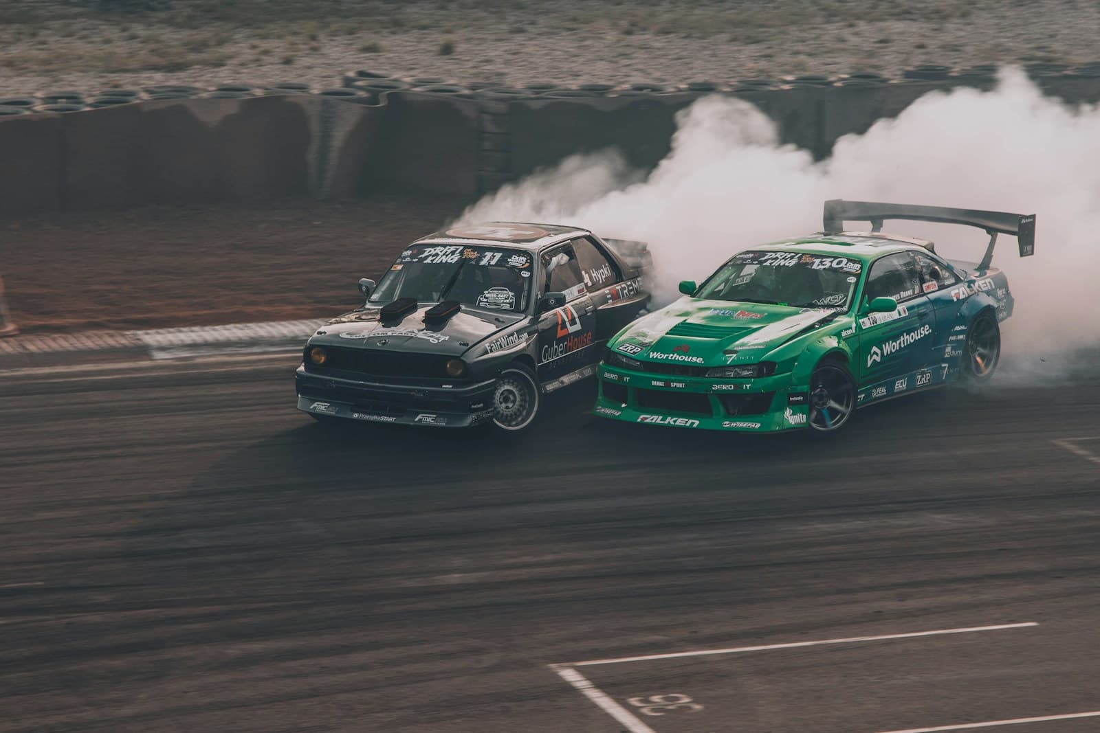 Two race cars drifting through a turn